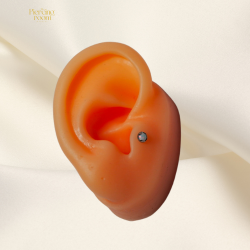 Aurora Opal Top gedragen in helixpiercing. Titanium top met witte opaalsteen, subtiel glanzend en elegant.