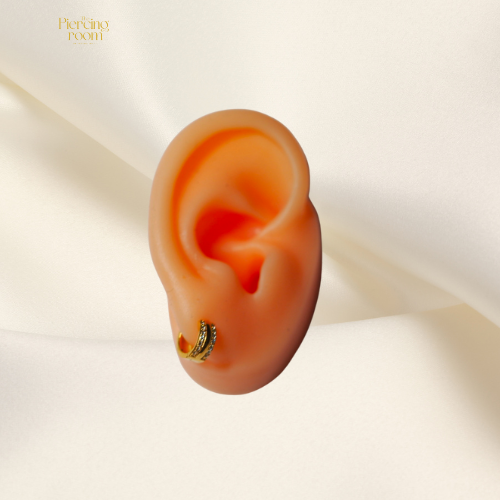 Double Row Huggie Hoops gedragen in oorlel. Goudkleurige oorringen met dubbele rij zirconia’s, elegant en modern design.