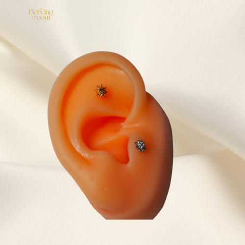 Sunray Zirconia Top gedragen in helixpiercing en in Tragus piercing. Gouden en zilveren threadless top met zonvormig design en sprankelende zirconia.