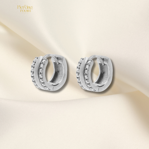 zilverkleurige chirurgisch stalen huggie hoops met dubbele rij zirconia’s. Luxe click oorringen met glanzende afwerking.