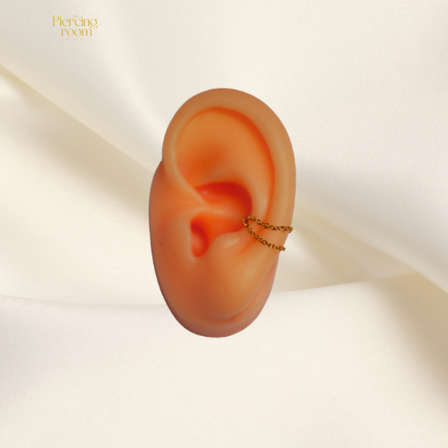 Double Layer Piercing Chain in goudkleurig chirurgisch staal. Gedragen in het oor als stijlvol piercingaccessoire met dubbele ketting.