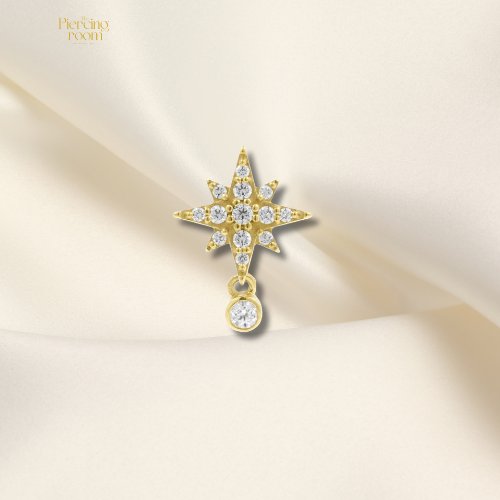 Goudkleurige threadless top van nikkelvrij staal met stervormige zirconia hanger. Luxe en speels design, geschikt voor diverse piercings.