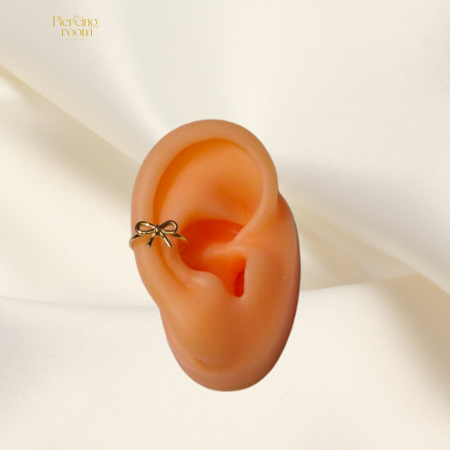 Gouden conch clicker piercing met strikdetail, gemaakt van nikkelvrij chirurgisch staal. Elegant design, eenvoudig open en dicht te klikken.