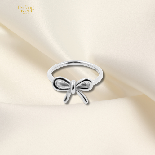 Zilveren conch clicker piercing met strikvorm, gemaakt van nikkelvrij chirurgisch staal. Tijdloos design, makkelijk te openen en sluiten.